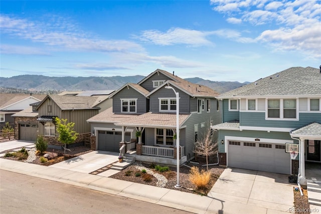 view of front facade with a garage, covered porch, a mountain view, and driveway