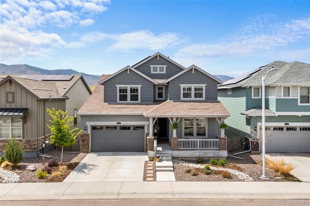 view of front of home with concrete driveway, a mountain view, covered porch, and a garage