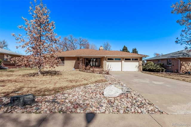 ranch-style house featuring a garage, a chimney, concrete driveway, and brick siding