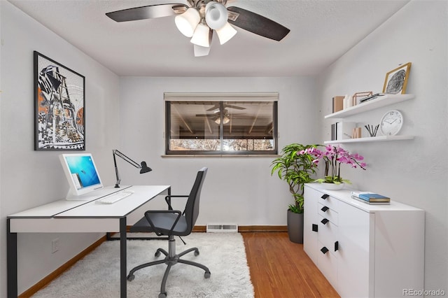 office with light wood-type flooring, visible vents, ceiling fan, and baseboards