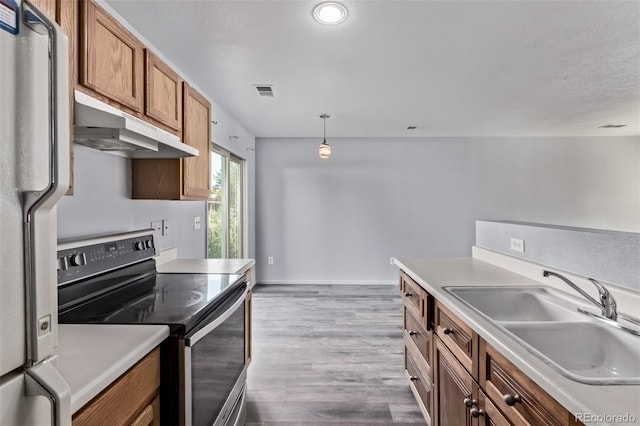 545 Tanager St, Brighton, CO 80601 - kitchen with stainless steel range with electric cooktop, under cabinet range hood, freestanding refrigerator, dark wood-type flooring, and brown cabinetry