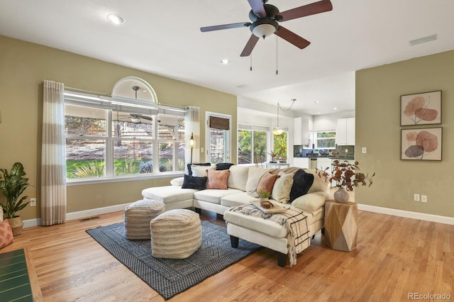 living room with ceiling fan, light wood-type flooring, and plenty of natural light