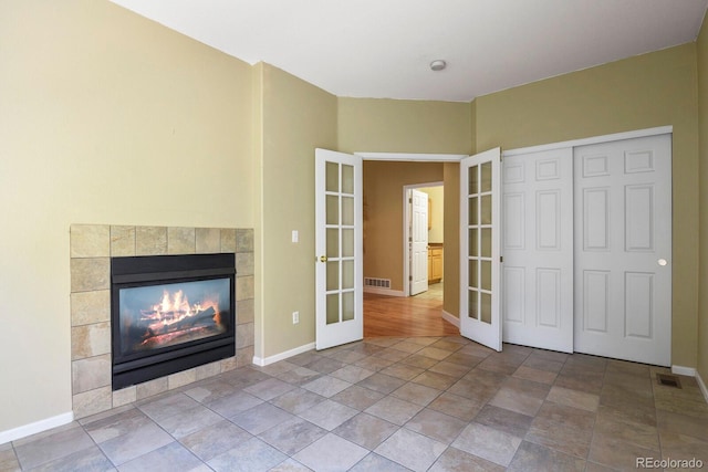 unfurnished living room featuring french doors and a tile fireplace