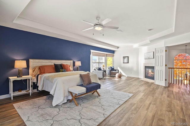 bedroom with ceiling fan, hardwood / wood-style flooring, and a raised ceiling