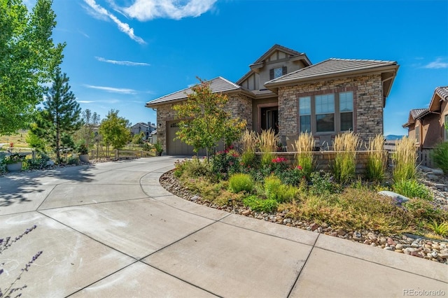 10731 Featherwalk Ln, Highlands Ranch, CO 80126 - view of front facade featuring stone siding, driveway, an attached garage, and a tiled roof