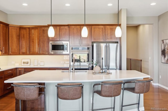 10731 Featherwalk Ln, Highlands Ranch, CO 80126 - kitchen with stainless steel appliances, dark wood-style flooring, a breakfast bar area, a sink, and light countertops