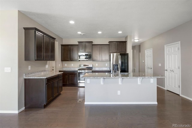 12210 Pine Post Dr, Parker, CO 80138 - kitchen featuring stainless steel appliances, dark brown cabinetry, an island with sink, recessed lighting, and dark wood-style flooring