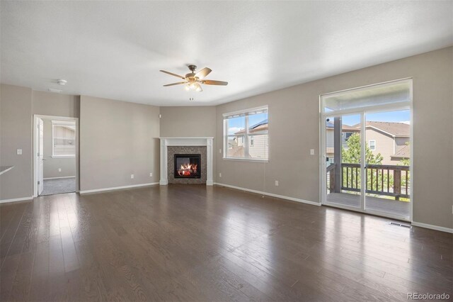 12210 Pine Post Dr, Parker, CO 80138 - unfurnished living room featuring ceiling fan, baseboards, dark wood finished floors, and a glass covered fireplace