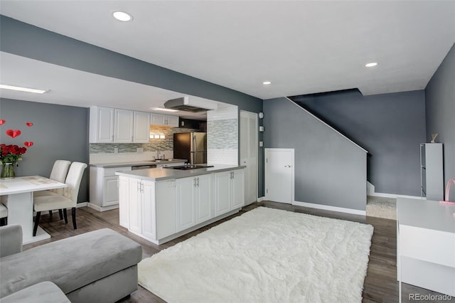 kitchen with white cabinets, light countertops, wood finished floors, and freestanding refrigerator