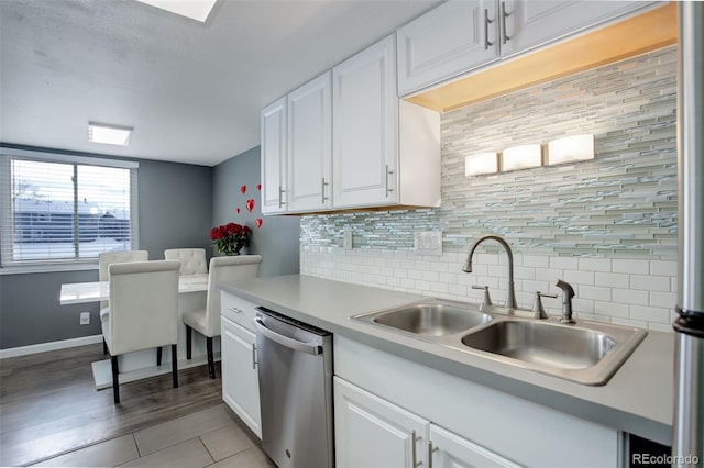 kitchen with light countertops, stainless steel dishwasher, a sink, and white cabinetry