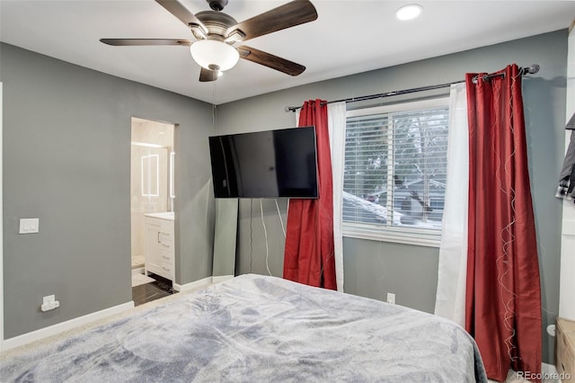 bedroom featuring a ceiling fan, ensuite bath, and baseboards