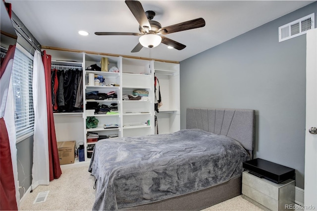 bedroom with light carpet, visible vents, and a ceiling fan