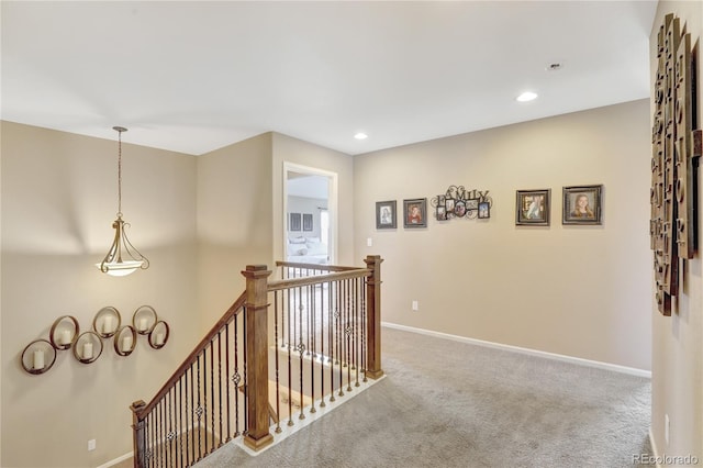 hallway featuring carpet floors, recessed lighting, baseboards, and an upstairs landing
