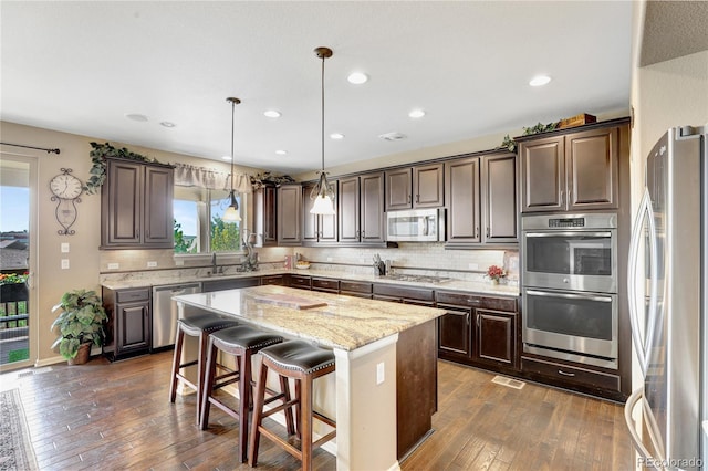 kitchen with decorative backsplash, dark wood finished floors, appliances with stainless steel finishes, and dark brown cabinetry