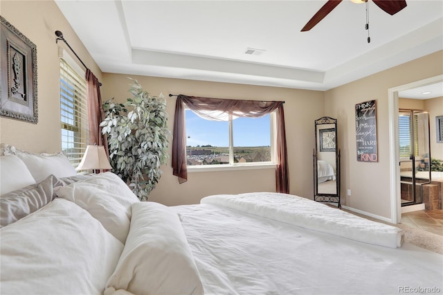 tiled bedroom featuring a raised ceiling, multiple windows, and visible vents