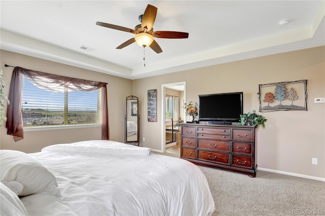 bedroom featuring ceiling fan, light carpet, baseboards, a tray ceiling, and visible vents