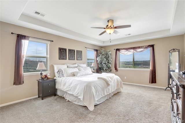 bedroom featuring visible vents, a tray ceiling, and light colored carpet