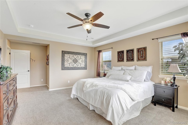 bedroom featuring baseboards, light colored carpet, and a raised ceiling
