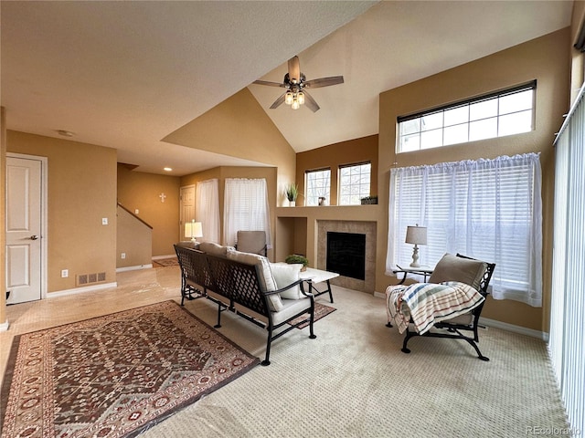 living room featuring high vaulted ceiling, light carpet, a tile fireplace, and ceiling fan