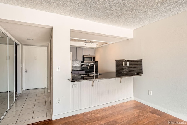 kitchen with sink, rail lighting, a breakfast bar, stainless steel appliances, and a textured ceiling