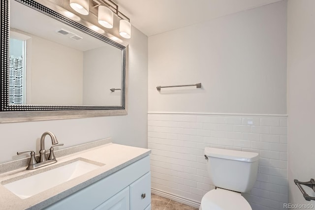 bathroom featuring vanity, tile walls, tile patterned floors, and toilet