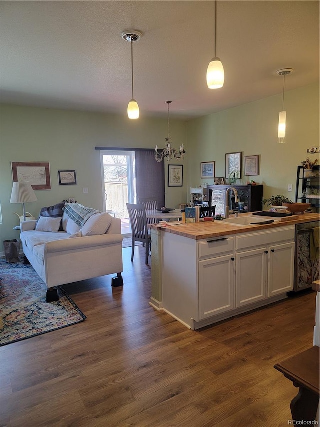 kitchen featuring a sink, white cabinets, open floor plan, wooden counters, and dark wood-style floors