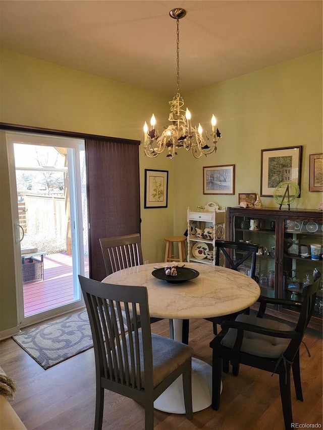 dining space with wood finished floors and an inviting chandelier