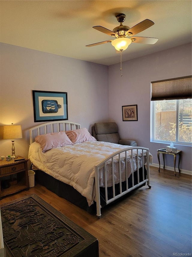 bedroom featuring wood finished floors, a ceiling fan, and baseboards