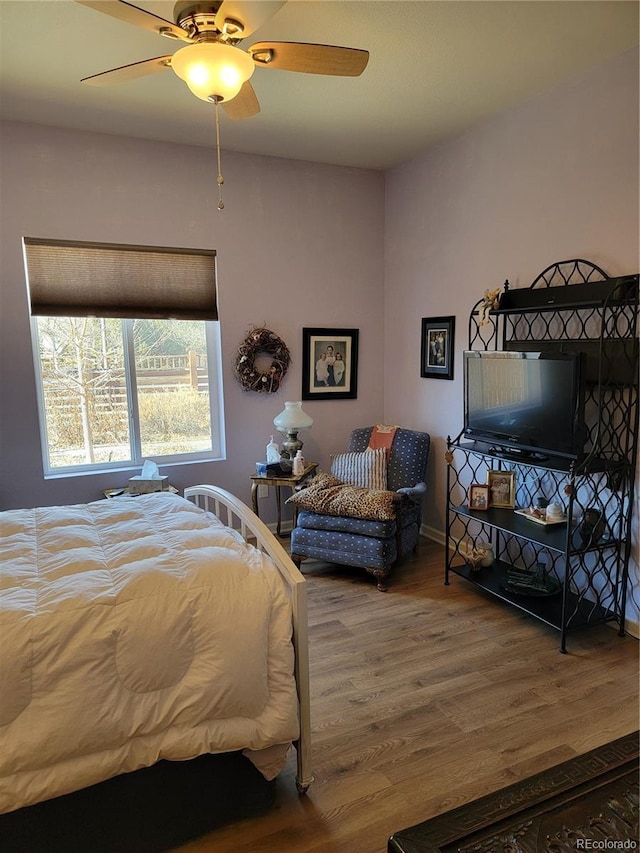 bedroom with ceiling fan, baseboards, and wood finished floors