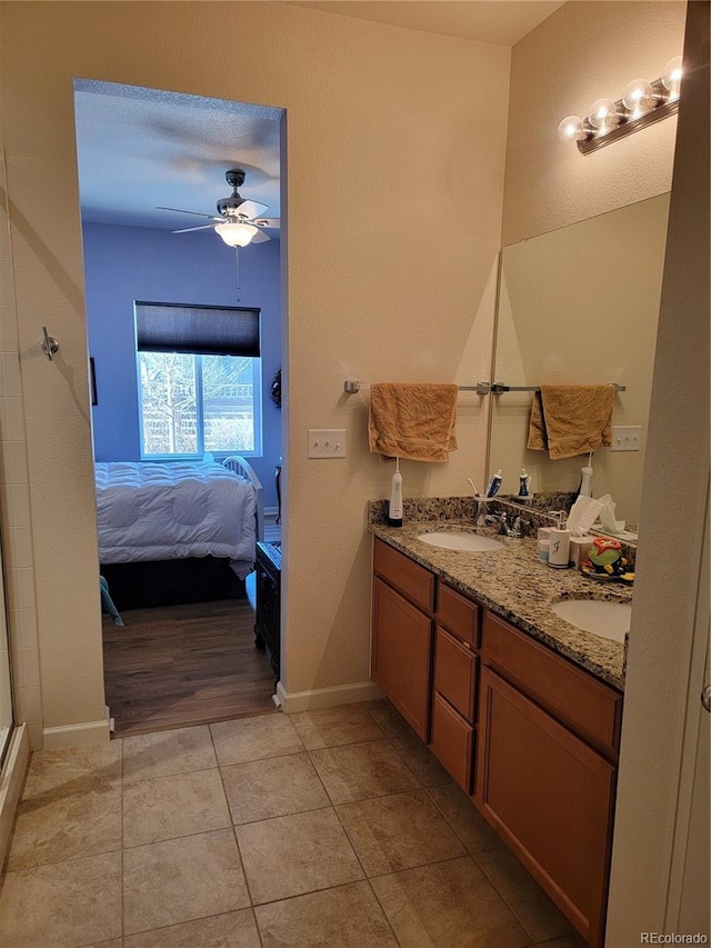 ensuite bathroom featuring double vanity, tile patterned flooring, connected bathroom, and a sink