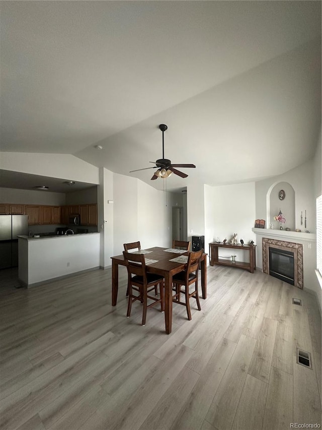 12235 E 2nd Dr, Aurora, CO 80011 - dining space with vaulted ceiling, light wood-style flooring, ceiling fan, and a fireplace