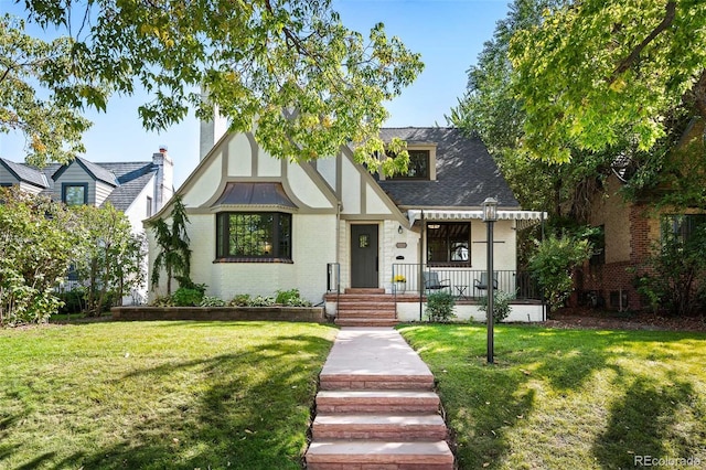 tudor-style house with a porch and a front yard