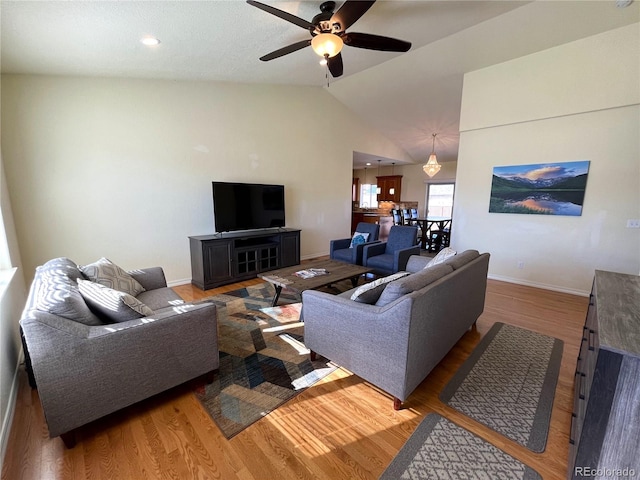 living room with hardwood / wood-style floors, ceiling fan, and vaulted ceiling