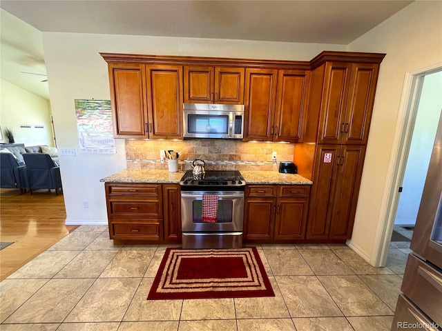 kitchen with tasteful backsplash, light stone countertops, ceiling fan, and stainless steel appliances