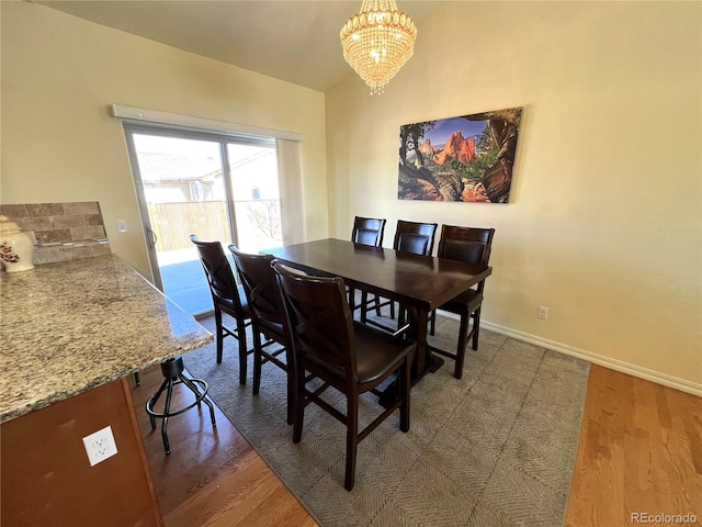 dining space featuring dark wood-type flooring and an inviting chandelier