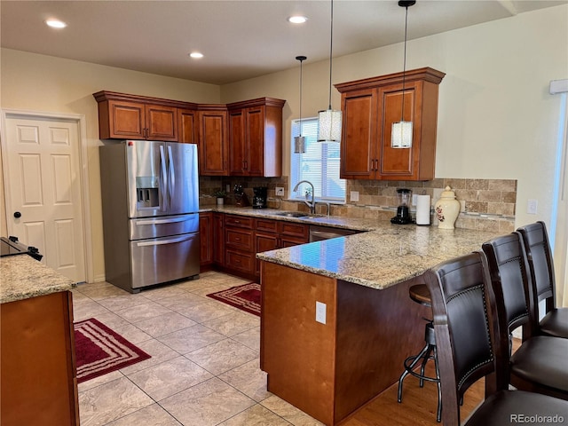 kitchen featuring sink, kitchen peninsula, backsplash, stainless steel fridge with ice dispenser, and pendant lighting