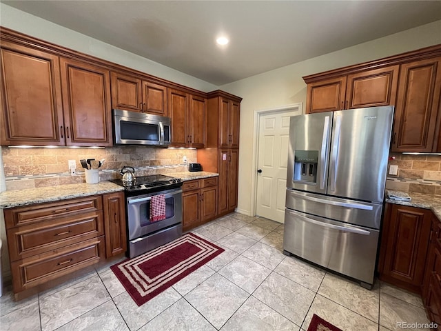 kitchen with appliances with stainless steel finishes, light tile patterned floors, backsplash, and light stone countertops