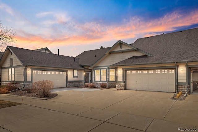 craftsman-style home featuring concrete driveway, an attached garage, stone siding, and a shingled roof