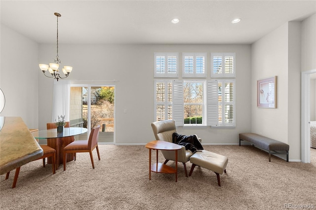 living area with plenty of natural light, a notable chandelier, and carpet