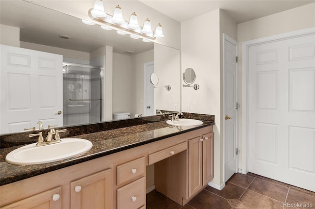 bathroom featuring tile patterned flooring, a stall shower, double vanity, and a sink