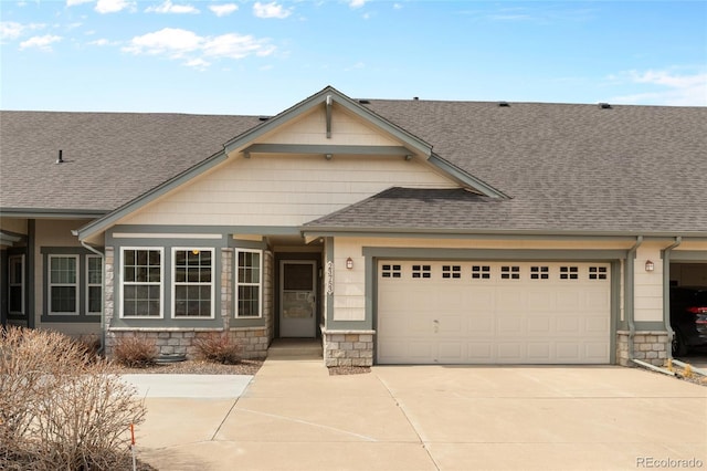 view of front of house with roof with shingles, driveway, a garage, and stone siding