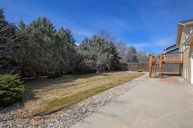 view of yard featuring a wooden deck, a patio, fence, and stairs