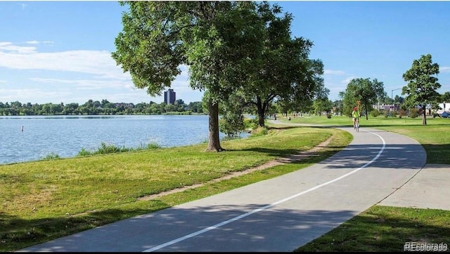 surrounding community with a water view and a lawn