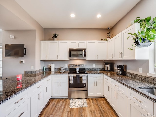 246 Ash St, Bennett, CO 80102 - kitchen with light wood finished floors, dark stone counters, stainless steel appliances, white cabinetry, and recessed lighting