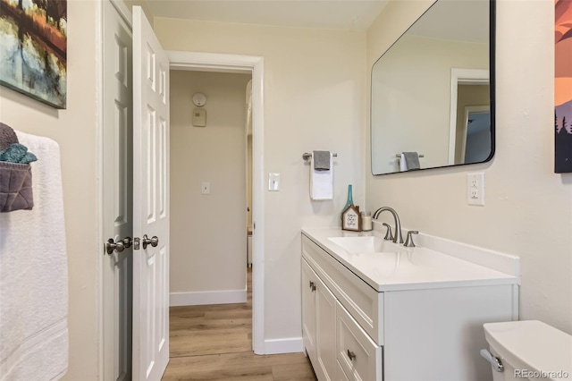 bathroom featuring toilet, vanity, baseboards, and wood finished floors