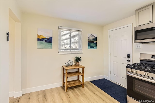 kitchen with stainless steel appliances, baseboards, and light wood finished floors