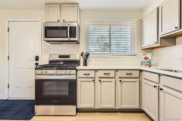 kitchen featuring appliances with stainless steel finishes, light countertops, light wood-style floors, and a sink