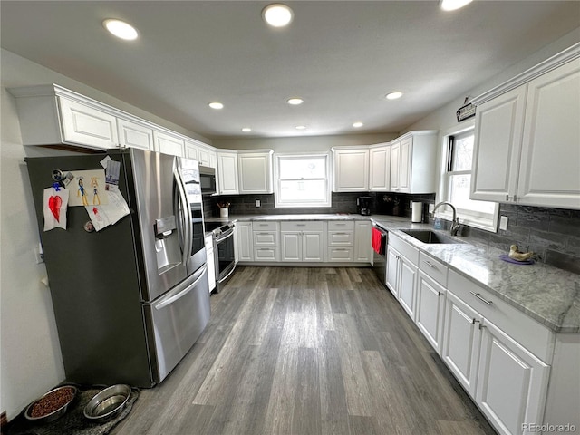 495 E Ave, Limon, CO 80828 - kitchen with appliances with stainless steel finishes, a sink, dark wood finished floors, decorative backsplash, and white cabinets
