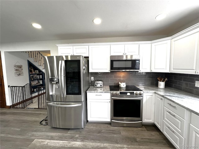 495 E Ave, Limon, CO 80828 - kitchen with stainless steel appliances, white cabinetry, decorative backsplash, light stone counters, and dark wood finished floors