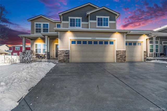 craftsman-style house featuring a garage, concrete driveway, a porch, and stone siding